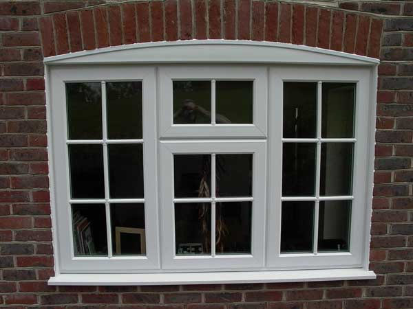 Traditional white flush sash window installed in a brick property with decorative glazing bars and arched head detail.